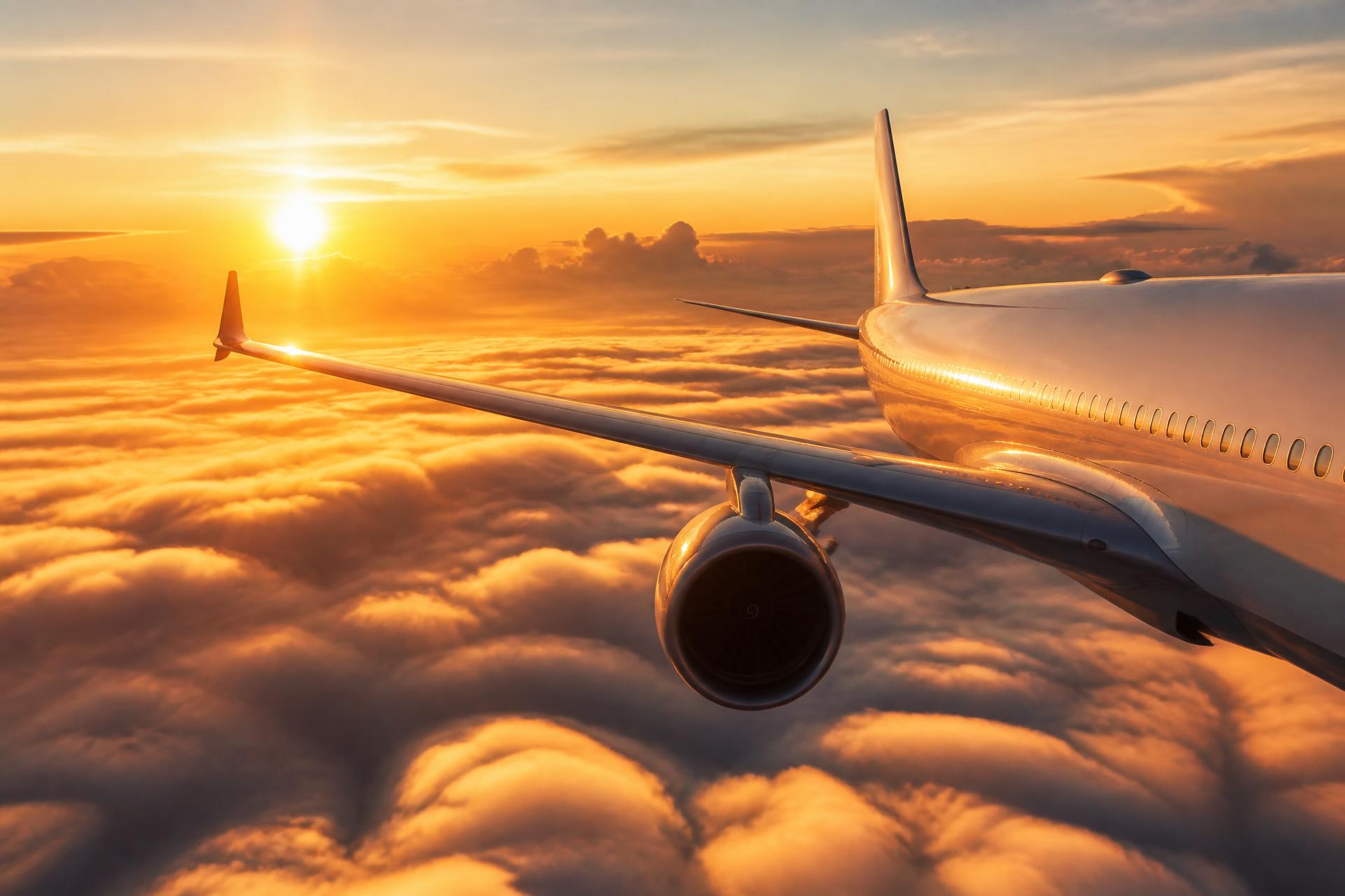 Passenger aircraft flying above golden clouds at sunrise